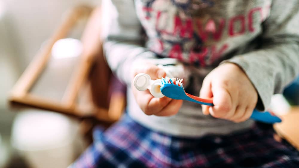 Child applying toothpaste to toothbush