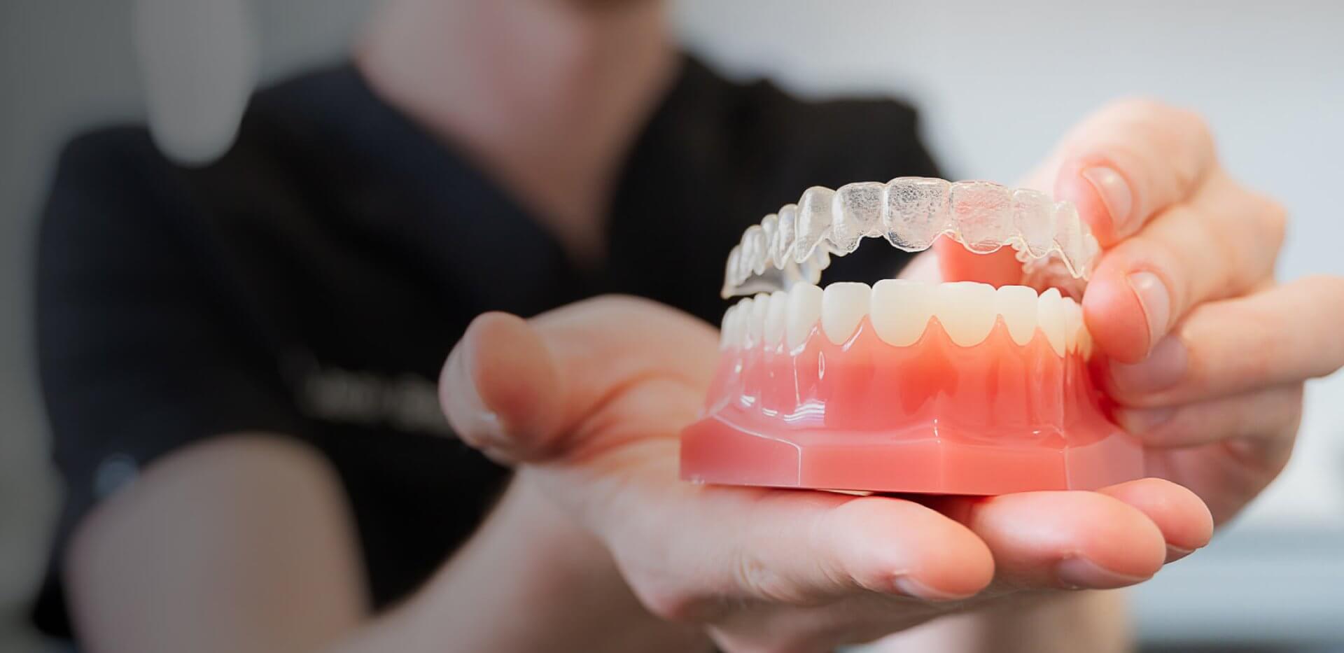 Dentist holding a clear aligner over a dental model