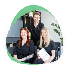 Three 123 Dental team members in black scrubs smiling together in the practice waiting area