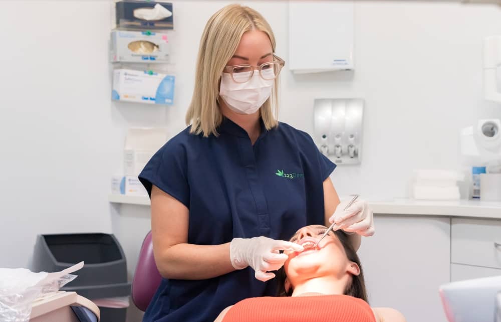 Young woman undergoing dental procedure, 123 Dental