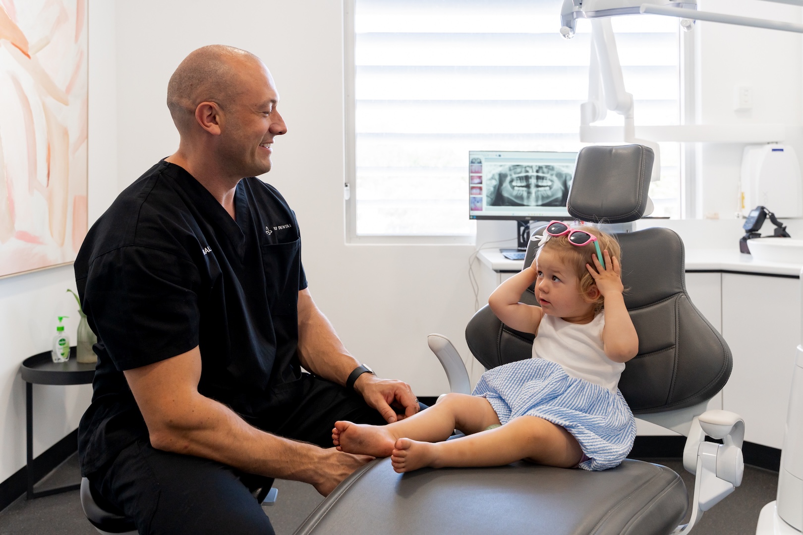 Dentist sitting beside a young child seated on the dental chair at 123 Dental