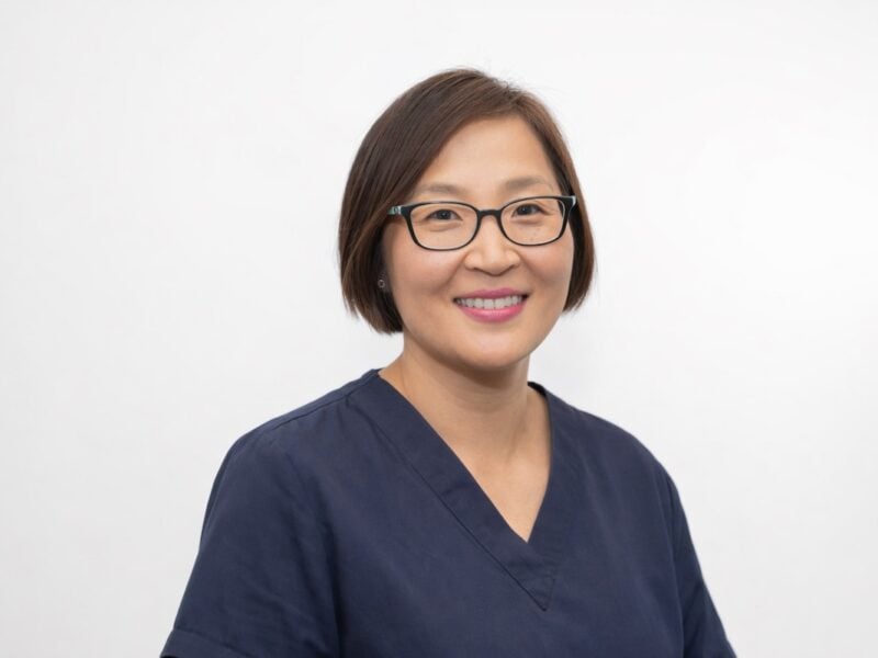 Dr Chae Park, specialist prosthodontist at 123 Dental, in navy scrubs against a white backdrop