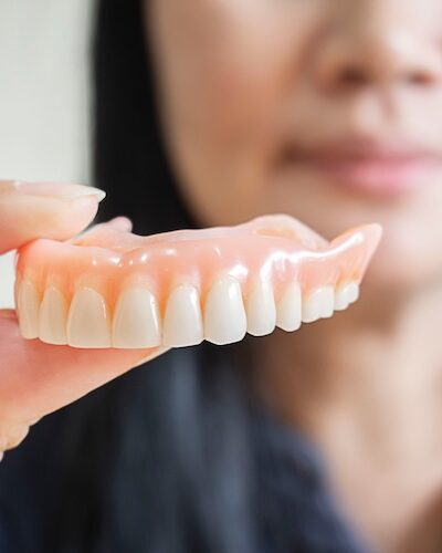 Happy asian woman be smile and holding dentures in hand