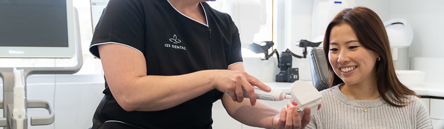 Dentist showing a patient a dental model while explaining root canal treatment