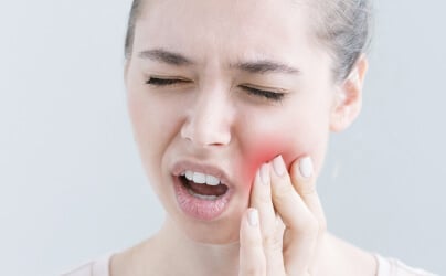 Woman holding her cheek in pain from a toothache