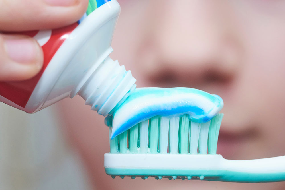 Adding toothpaste to toothbrush