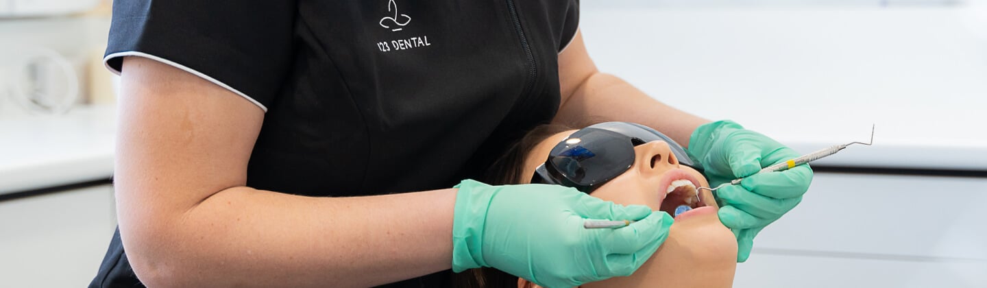 Dental clinician working on a patient's front teeth while the patient wears protective eyewear