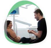 Dentist talking with a smiling patient reclined in the treatment chair during a consultation